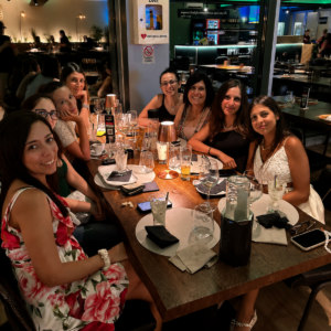 Un gruppo di amiche sorride al tavolo con la pulsantiera del Kanta Game durante la serata musicale del martedì da 140 Grammi Sestu.