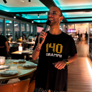 Il presentatore con la maglia 140 Grammi conduce il Kanta Game al microfono nella sala di Sestu illuminata dalle luci della serata del martedì.
